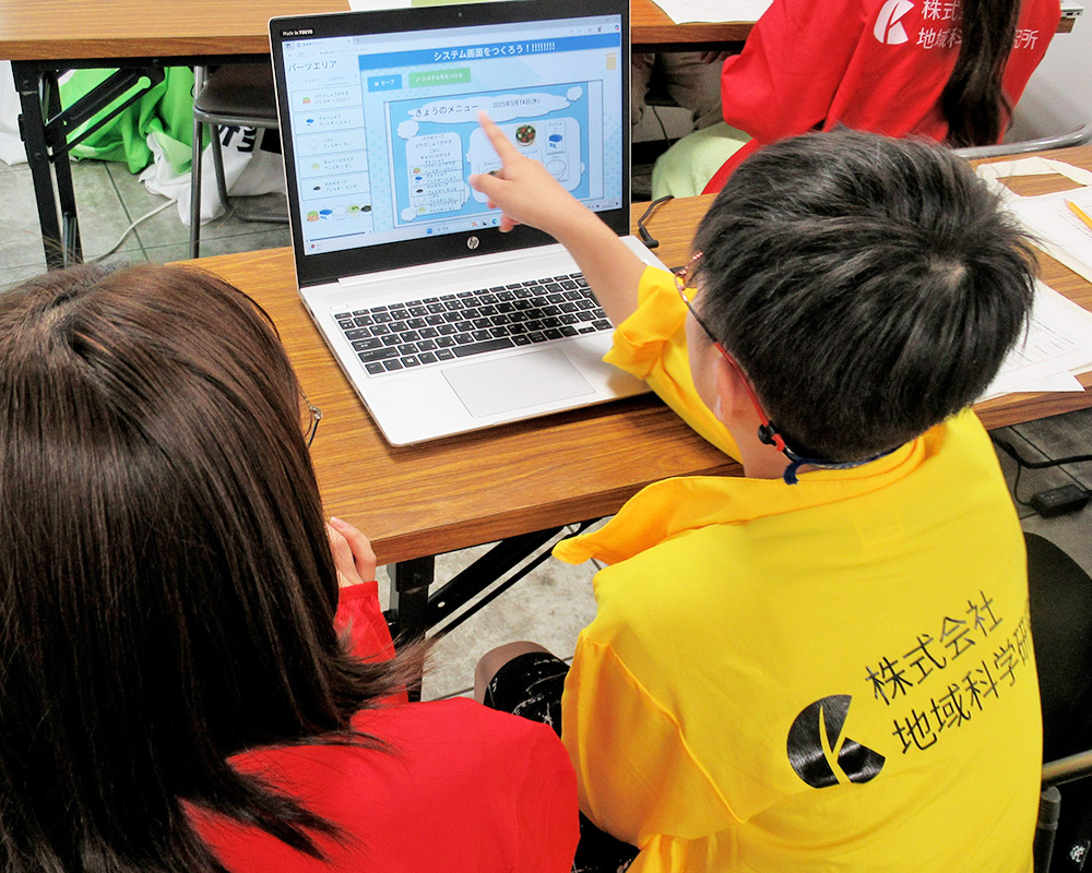 パソコンを指さしながら説明する男の子