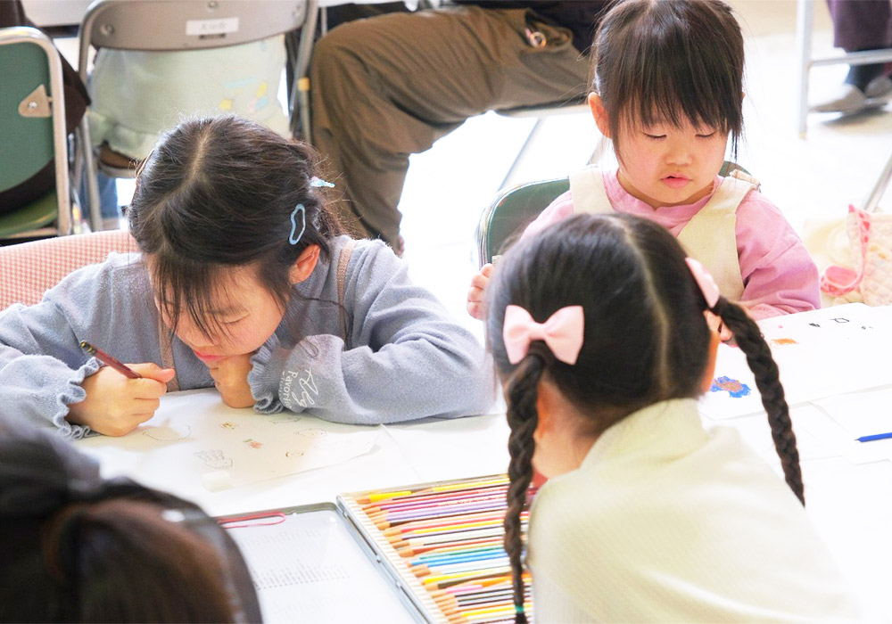 色鉛筆を持って紙に向かう子どもたち