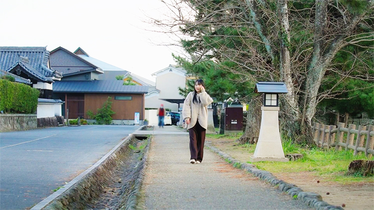 日出のまちを歩く女性