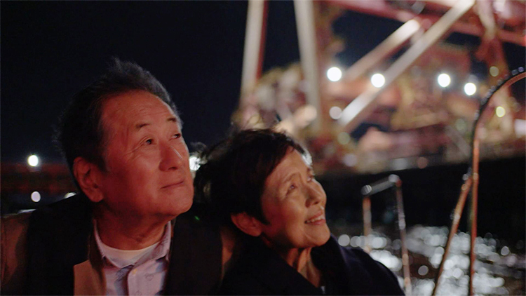 夜の灯りを見つめる老夫婦
