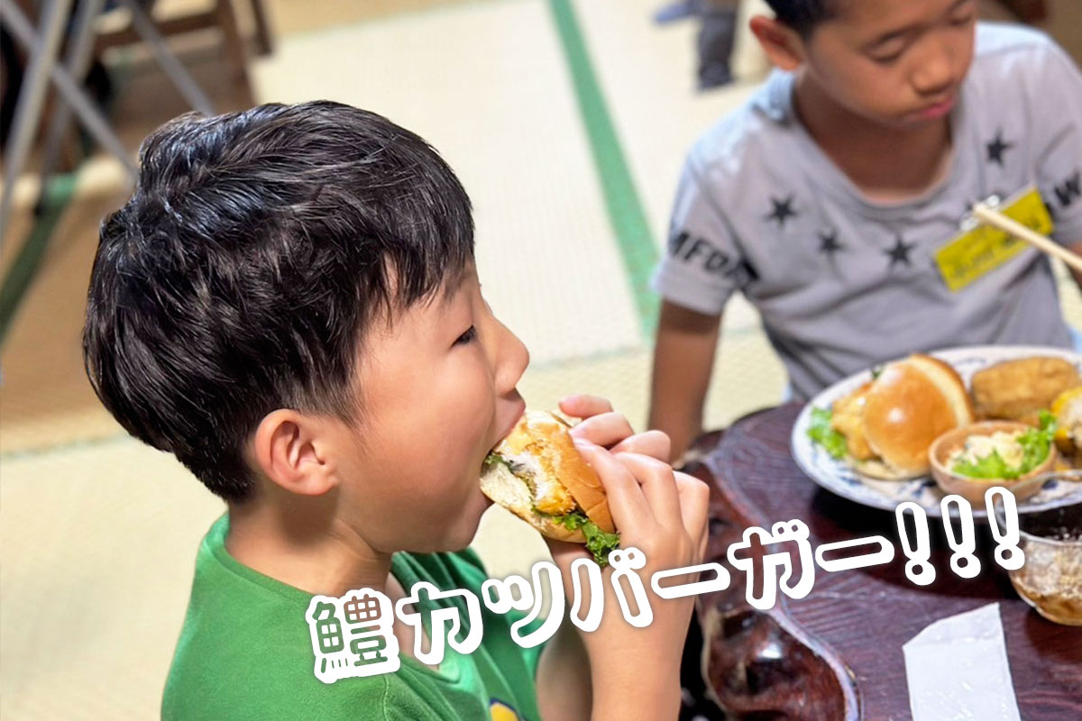 鱧カツバーガーをかじる男の子